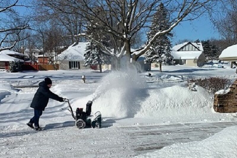 man using snow blower in winter