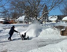 man using snow blower in winter