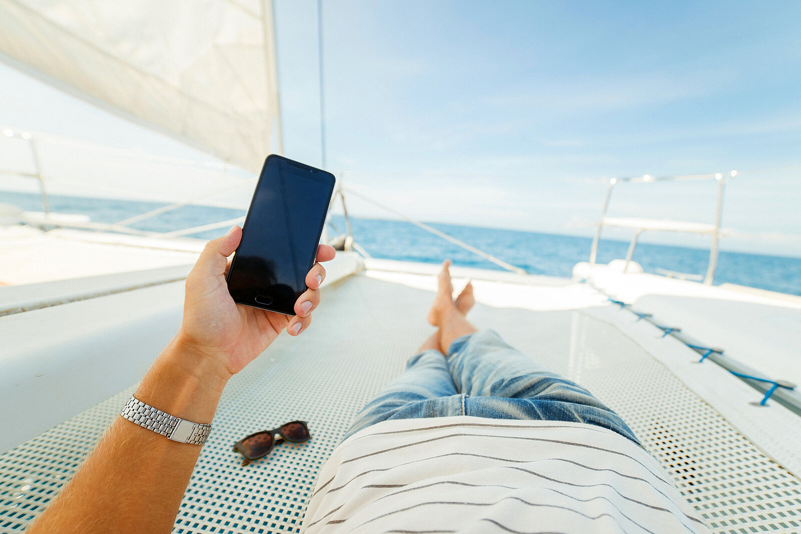man laying in yacht looking at his phone